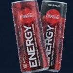 Zwei gekühlte Coca-Cola-Energy-Dosen stehen nebeneinander vor dunklem Hintergrund. Eine Dose ist rot (Classic), die andere schwarz mit der Aufschrift „No Sugar“. Beide sind mit Wassertropfen bedeckt und zeigen das Coca-Cola-Logo sowie den Schriftzug „Energy“.